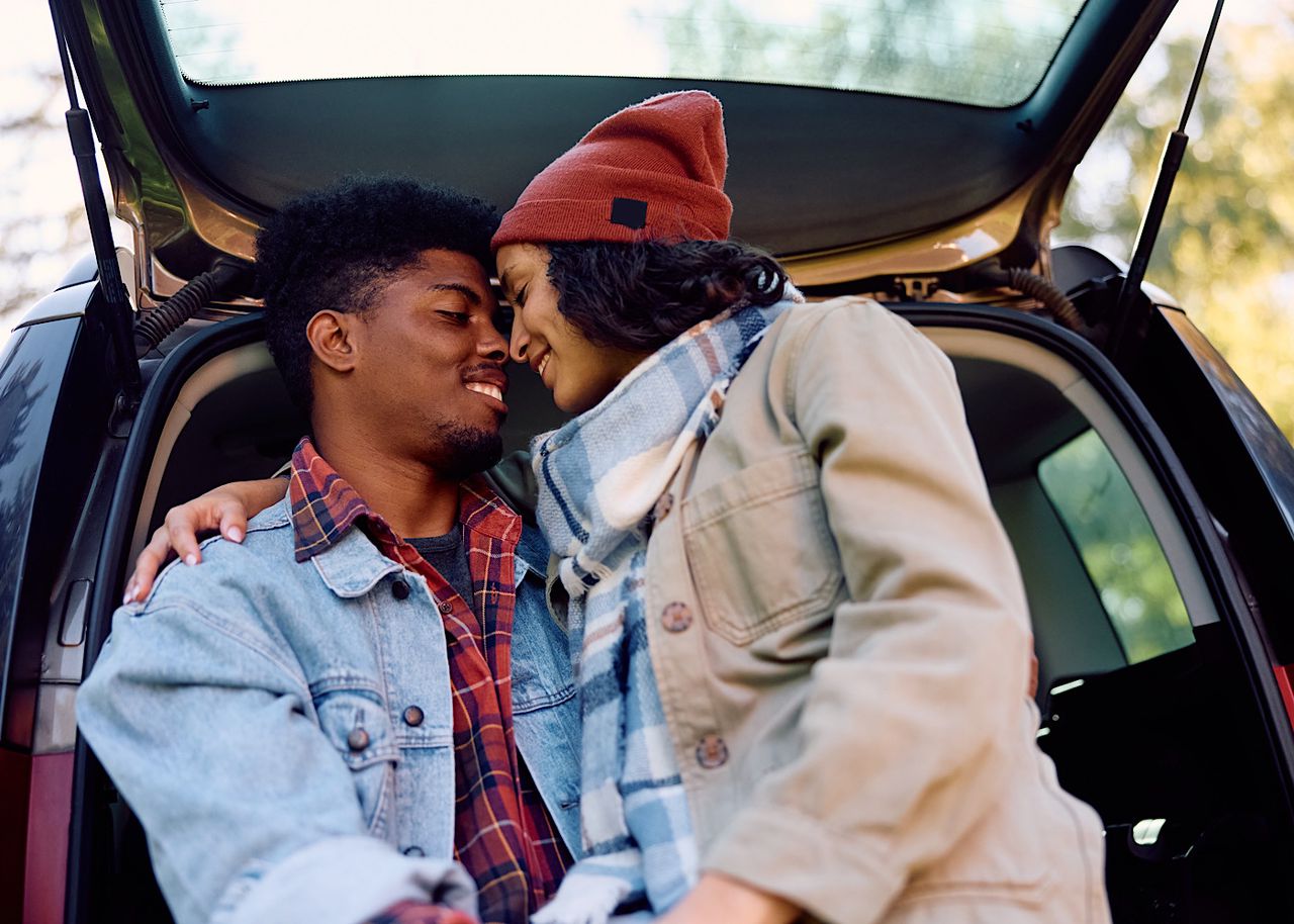 Young romantic couple enjoying in their love in car trunk in nature. by drazenphoto
