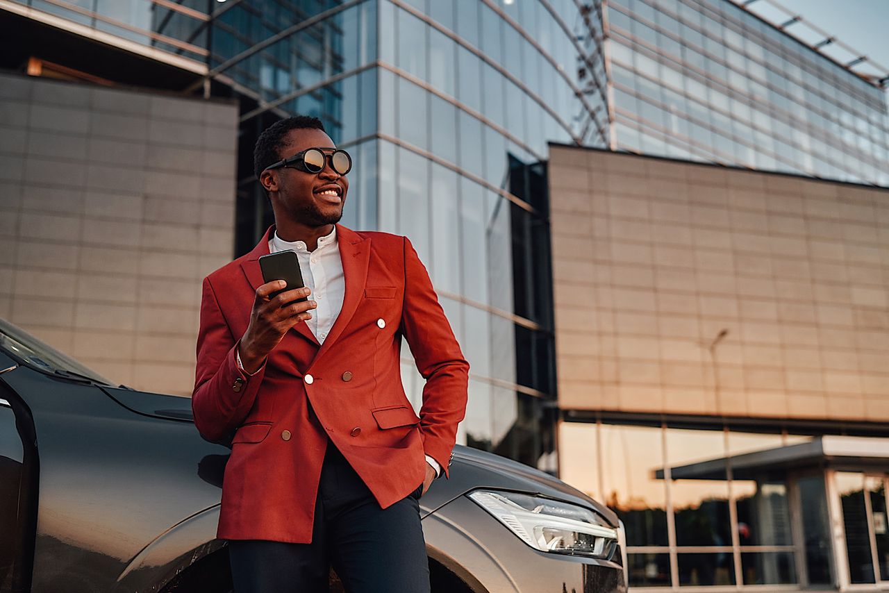 Confident black businessperson posing leaning his car by fxquadro