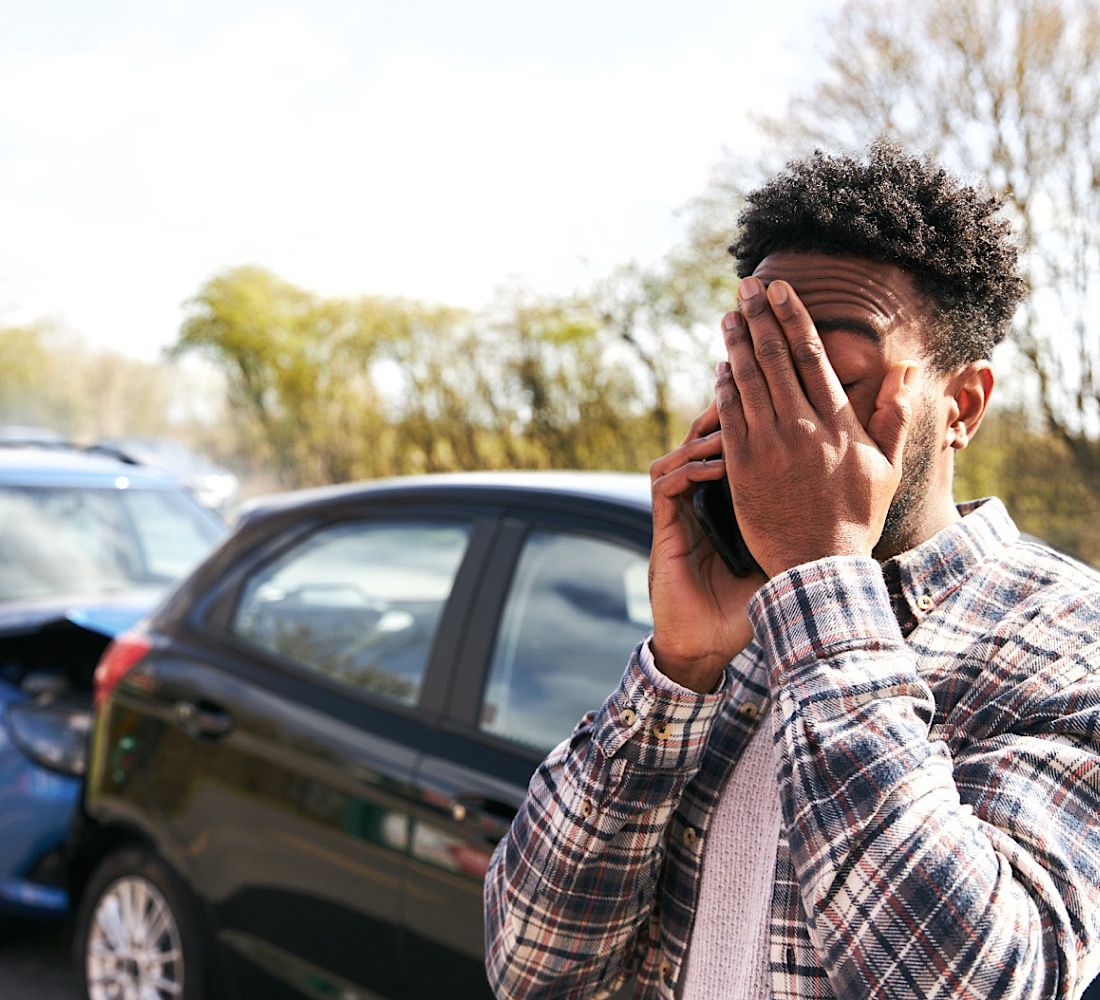 Young Male Driver Calling Car Insurance Company On Mobile Phone After Road Traffic Accident by SouthworksStock