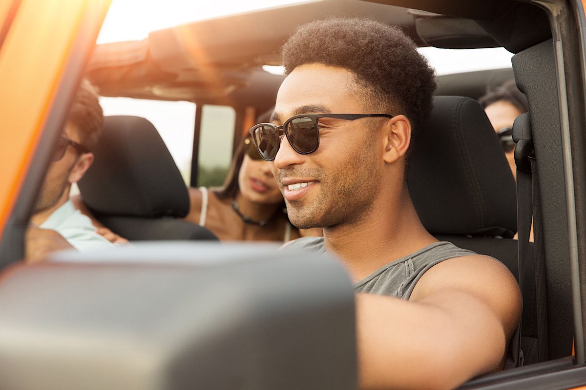 Smiling Man Driving with Friends in Convertible Car by vadymvdrobot